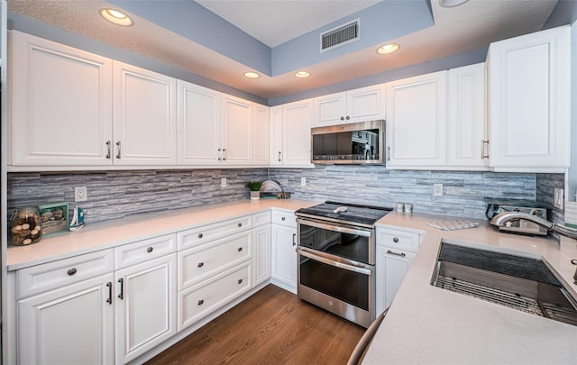 kitchen featuring stainless steel appliances, light countertops, visible vents, and decorative backsplash