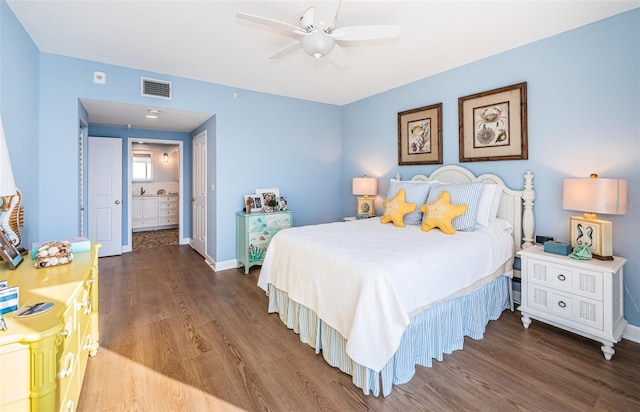 bedroom featuring ensuite bath, wood finished floors, visible vents, and baseboards