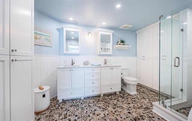 full bath with a stall shower, a wainscoted wall, a sink, and toilet