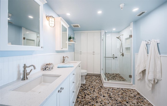 full bathroom featuring a wainscoted wall, a sink, visible vents, and a shower stall