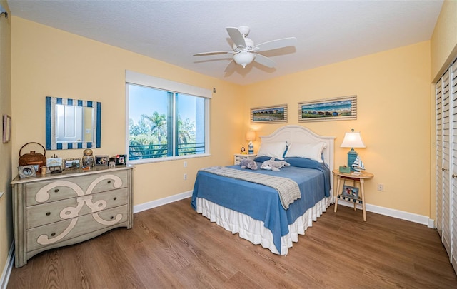 bedroom with ceiling fan, baseboards, and wood finished floors