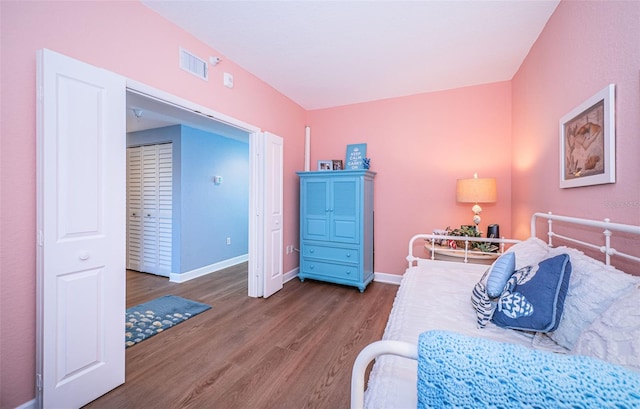 bedroom with baseboards, visible vents, and wood finished floors