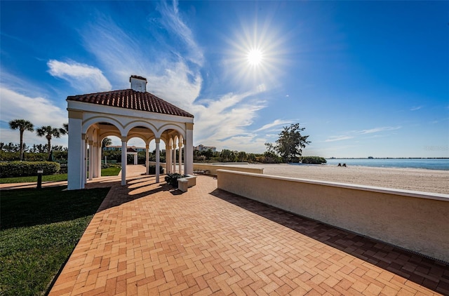 view of property's community featuring a water view, a yard, a beach view, and a gazebo