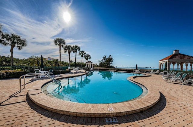 community pool with a patio area, fence, and a gazebo