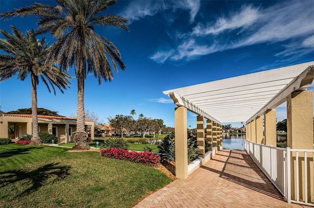 exterior space with a water view, fence, and a pergola