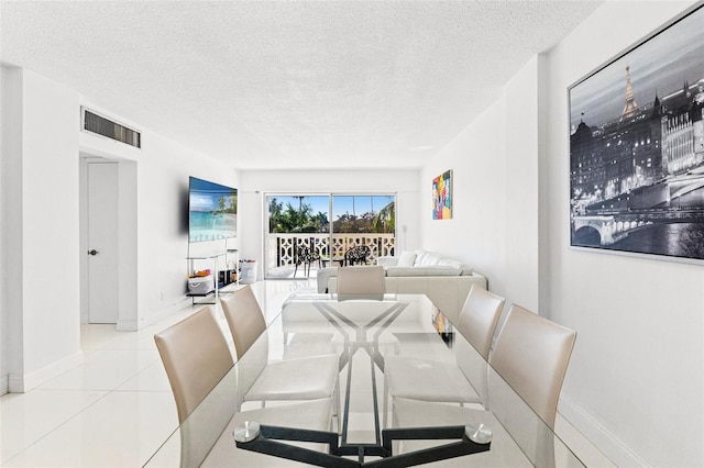 tiled dining area featuring visible vents, a textured ceiling, and baseboards