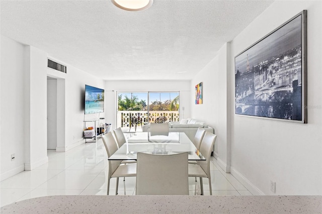 tiled dining area featuring baseboards, visible vents, and a textured ceiling