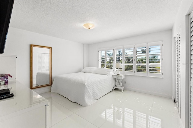 tiled bedroom with a textured ceiling and baseboards