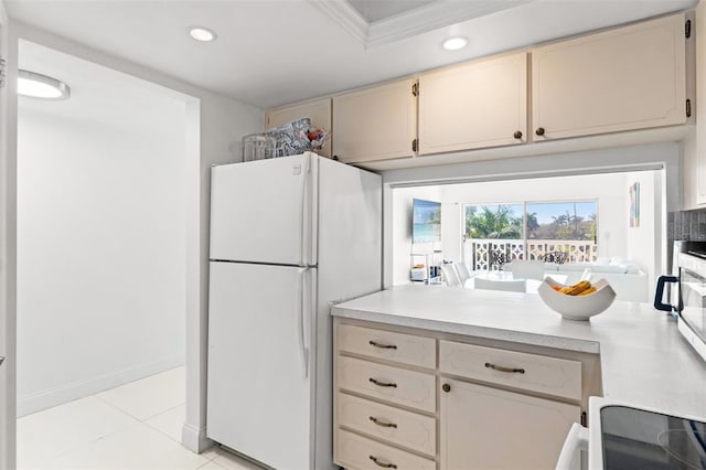 kitchen featuring light tile patterned floors, freestanding refrigerator, cream cabinets, light countertops, and recessed lighting