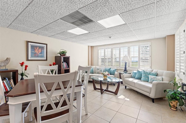 living room featuring visible vents, a drop ceiling, and light tile patterned floors