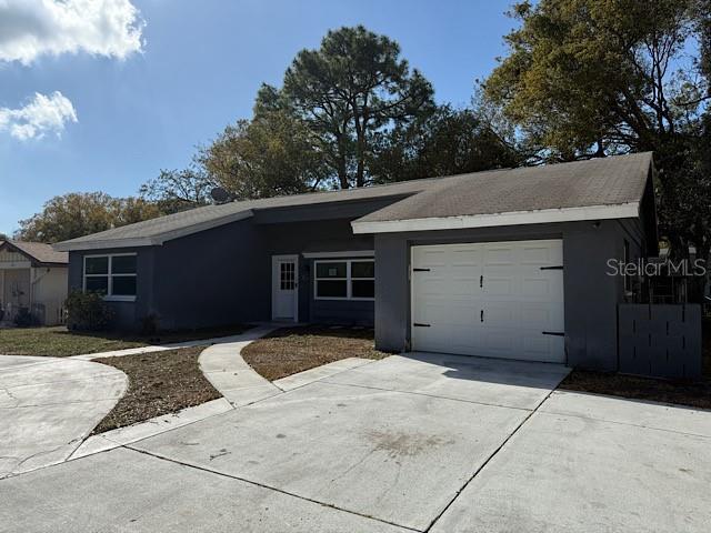 ranch-style house with a garage, driveway, and stucco siding