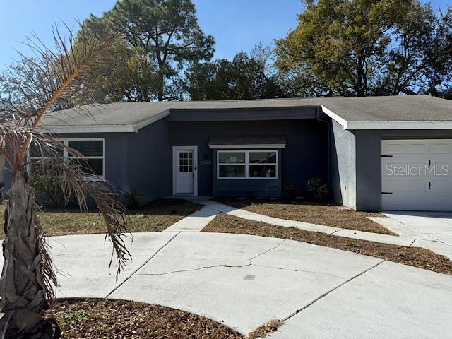 view of front of house with a garage, concrete driveway, and stucco siding