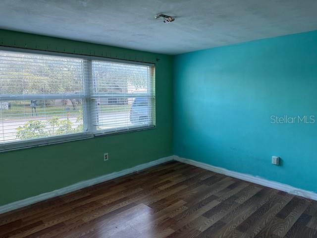 empty room featuring dark wood finished floors and baseboards