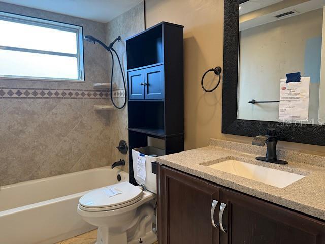 bathroom with toilet, shower / bath combination, tile patterned flooring, and vanity