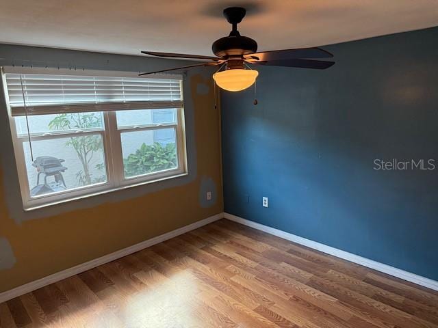 spare room with baseboards and wood finished floors