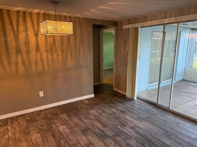 spare room featuring wood walls, baseboards, and wood finished floors