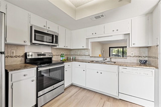 kitchen with light wood-style floors, appliances with stainless steel finishes, white cabinets, and a sink