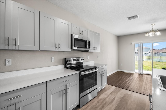 kitchen with visible vents, gray cabinets, stainless steel appliances, light countertops, and light wood-type flooring