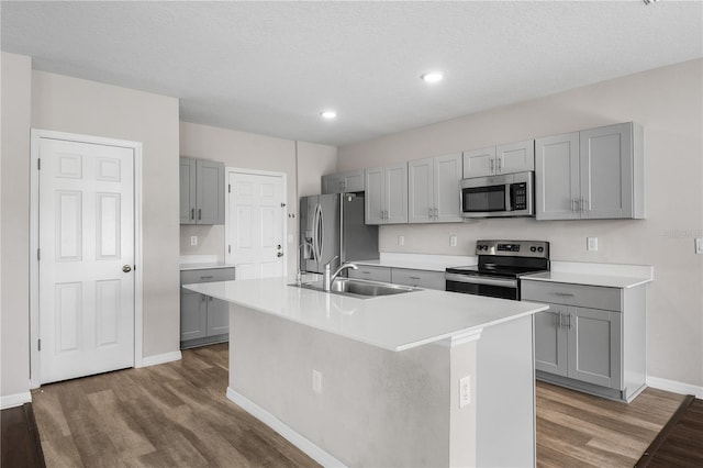 kitchen with a sink, appliances with stainless steel finishes, wood finished floors, and gray cabinets