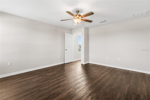 spare room featuring dark wood-style floors, ceiling fan, visible vents, and baseboards