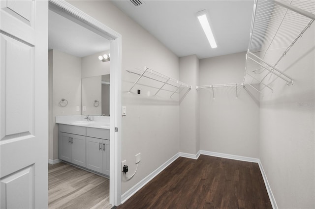 walk in closet featuring a sink, visible vents, and wood finished floors