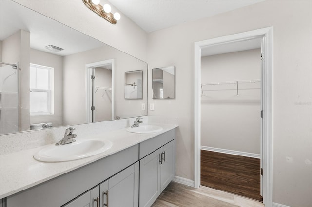 bathroom featuring double vanity, visible vents, a sink, and wood finished floors