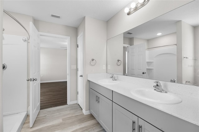 bathroom featuring double vanity, visible vents, a sink, and wood finished floors