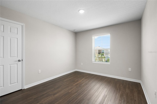 unfurnished room with dark wood finished floors, a textured ceiling, and baseboards