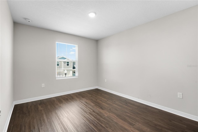 spare room featuring dark wood-style floors, baseboards, and a textured ceiling