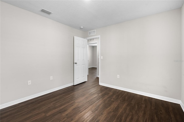 unfurnished room featuring baseboards, a textured ceiling, visible vents, and dark wood-type flooring