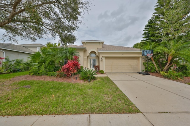 mediterranean / spanish home with a garage, concrete driveway, a front lawn, and stucco siding