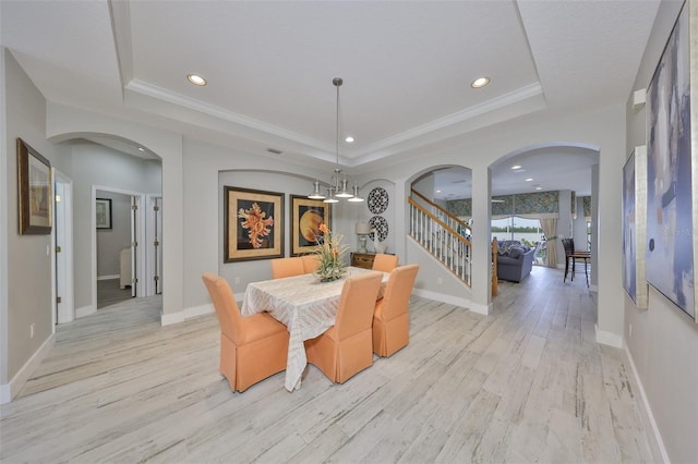 dining room featuring stairway, arched walkways, and a raised ceiling