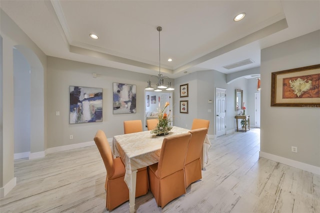 dining room with baseboards, arched walkways, a tray ceiling, light wood-type flooring, and recessed lighting