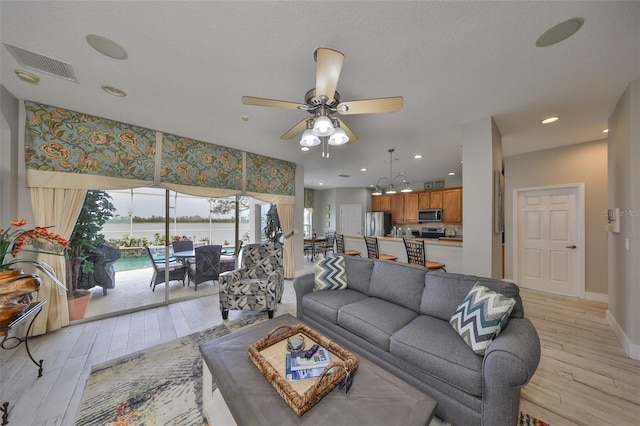 living room with baseboards, a sunroom, visible vents, and light wood-style floors