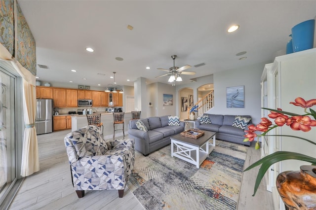 living area featuring light wood finished floors, visible vents, arched walkways, stairs, and recessed lighting