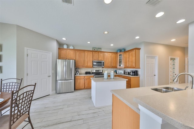 kitchen featuring stainless steel appliances, light countertops, glass insert cabinets, a kitchen island with sink, and a sink