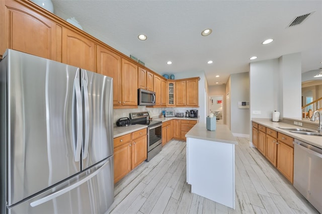 kitchen featuring visible vents, glass insert cabinets, stainless steel appliances, light countertops, and a sink