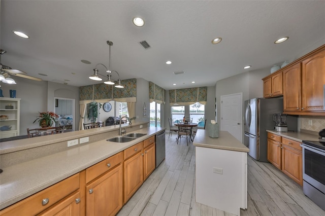 kitchen with brown cabinets, appliances with stainless steel finishes, light countertops, and a sink