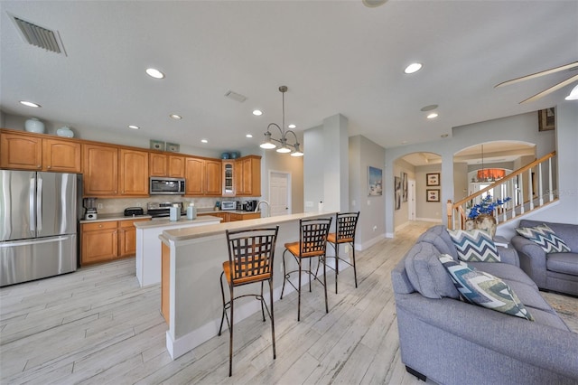 kitchen with visible vents, glass insert cabinets, open floor plan, stainless steel appliances, and light countertops