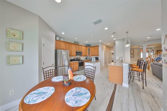 dining space with arched walkways, recessed lighting, visible vents, light wood-style flooring, and stairs