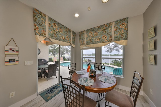 dining room featuring a sunroom, baseboards, and wood finished floors