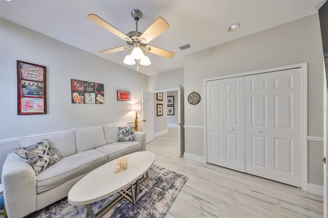 living area with lofted ceiling, visible vents, light wood-style floors, a ceiling fan, and baseboards