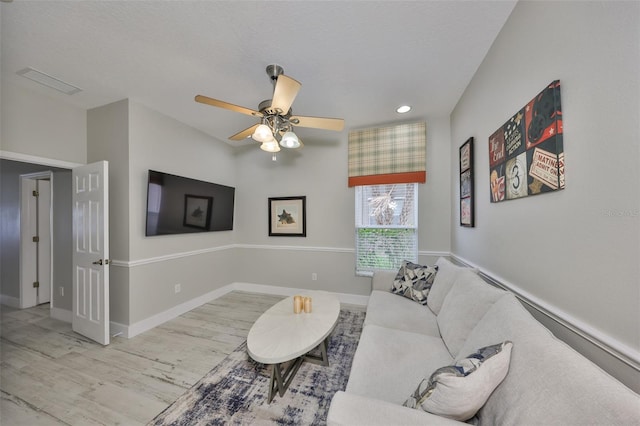 living room featuring a ceiling fan, light wood-type flooring, visible vents, and baseboards