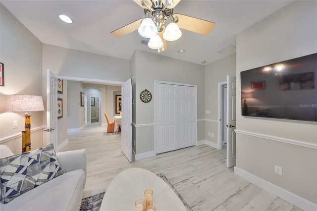 interior space featuring arched walkways, visible vents, ceiling fan, light wood-type flooring, and baseboards