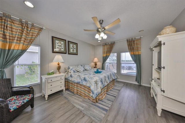 bedroom with light wood-style floors, multiple windows, baseboards, and a ceiling fan