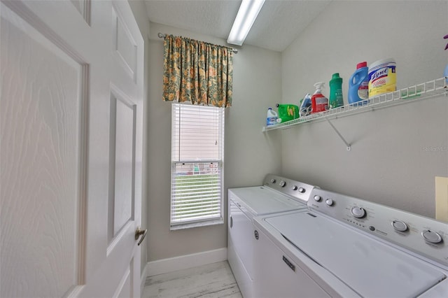 washroom featuring washing machine and dryer, laundry area, a textured ceiling, and baseboards