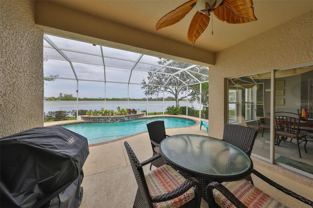 pool with a patio area, ceiling fan, a water view, and glass enclosure