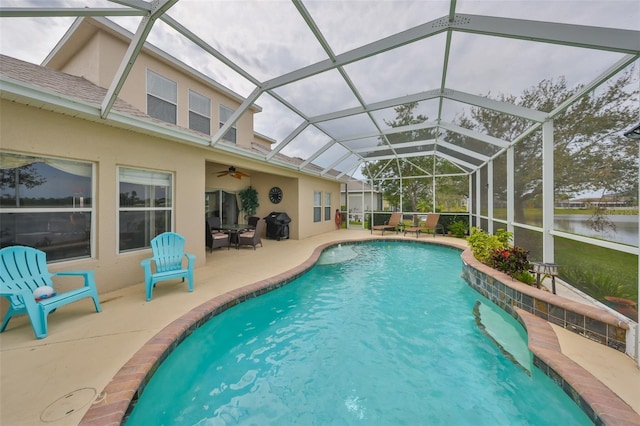 pool featuring glass enclosure, a patio area, and a water view