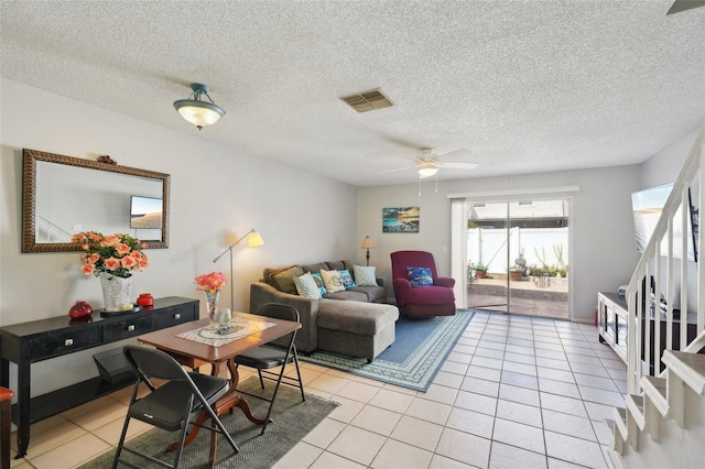 living area featuring a ceiling fan, visible vents, a textured ceiling, and light tile patterned flooring