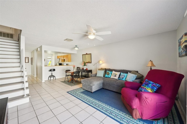 living room with visible vents, ceiling fan, stairway, a textured ceiling, and light tile patterned flooring